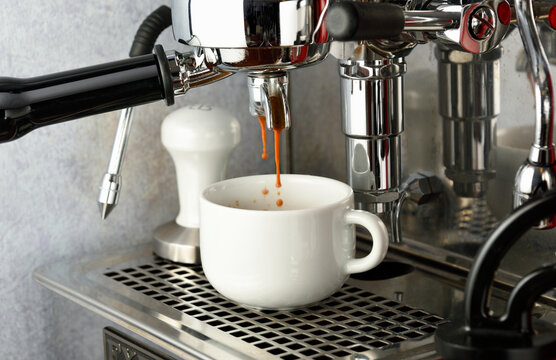Espresso extraction into white ceramic cup by professional espresso machine with E61 group head