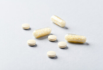 Fototapeta na wymiar Vitamin C tablets and capsules on bright paper background. Soft focus. Close up. Copy space. 