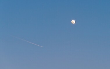 In the blue sky, the moon and the plane