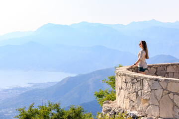 Young tourist woman enjoying view of Kotor bay in Montenegro in mountains - obrazy, fototapety, plakaty