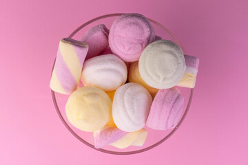 Colored marshmallows in a vase on a pink background. Flat lay.