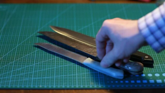 man lays out large kitchen knives on the table for sharpening