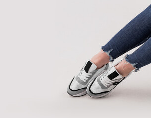Women's legs in stylish sports shoes on a white background