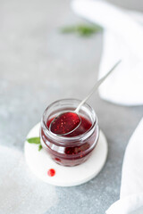 homemade raspberry jam in a glass jar with spoon