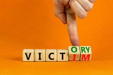 From victim to victory symbol. Businessman turns wooden cubes and changes concept words Victim to...