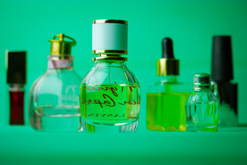 Different bottles of eau de toilette, perfumes, fragrances on green background. Cosmetic essential oil in bottles, jars. Cosmetics for beauty care. Set of vials for perfume. Aroma oils, aromatherapy.
