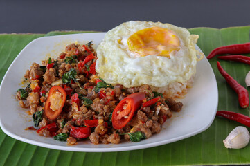 Rice with pork stir fried with basil and fried egg on black background, Thai food, Street food.