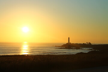 The yellow sunset with the lighthouse on the ocean