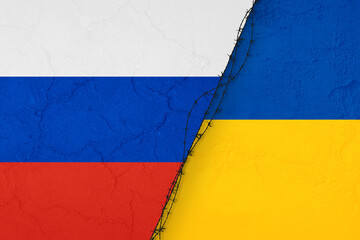 Bandiera ucraine e bandiera russa rappresentate su muro divise da un filo spinato.