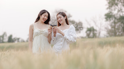 two young asian women friends take walking relax and drink coffee cup in her hand at barley field agriculture demonstration plot chiangmai province