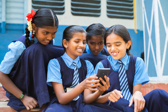 Group Of Smiling Girl Kids Busy Using Mobile Phone At School Corridor During Break - Concpet Of Smartphone Addiction, Using Social Media And Technology