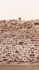Muro de piedra rocosa rojiza en centro de pueblo europeo