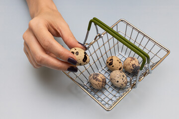 female hand puts quail eggs in a basket