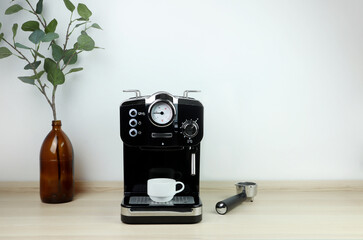 black modern design coffee machine is on wooden table and white cement wall background in the...