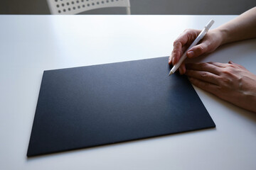 Hands hold a black sheet for inscriptions and advertising on a light background. Business and financial concept. Place for layout