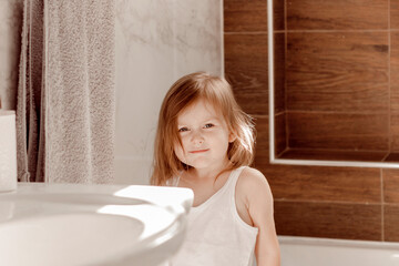 Obraz na płótnie Canvas Cute toddler wear casual white clothes brushing teeth in bathroom