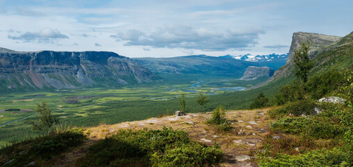 Panoramic scenic view of glacial Rapadalen river delta valley with Skierffe rock summit at Sarek...