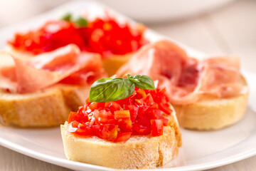 Italian appetizer bruschetta with Parma ham and fresh tomatoes on a plate - obrazy, fototapety, plakaty
