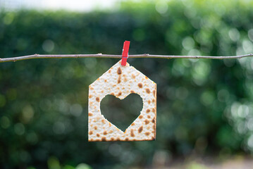 Matzah in shape house with heart on blurry green background. Traditional of Jewish Holiday on...