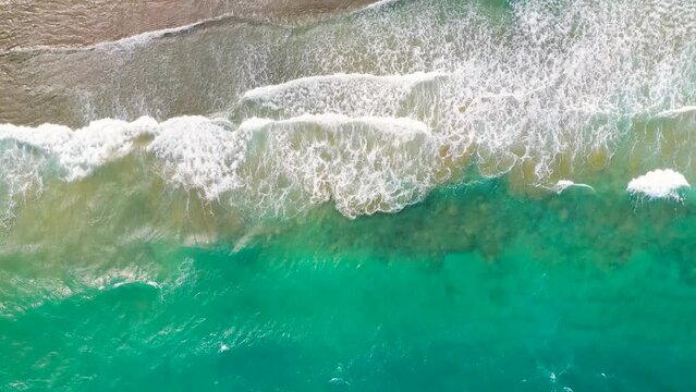 Aerial view of the Mediterranean coast, waves reach the deserted sandy beach. Beautiful vacation and tourism destination in Crete, Greece.