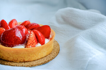 Birthday at home in bed alone. Lazy cozy holiday. Light airy gray neutral view. Bright tart with strawberries and butter cream on a textile, bakery, dessert. Simple template. Positive emotions, joy.