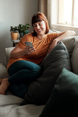 Obraz premium I hope theyre excited for our night out. Shot of an attractive young woman using her cellphone while relaxing on the sofa at home.