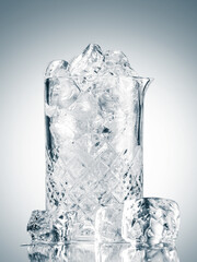Glass tray full of ice cubes on a light background on a reflective surface. Ice bucket with copy space.