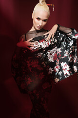 Stylish girl posing in a colored classic suit on a red background