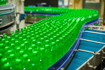 Beverage factory interior. Conveyor flowing with bottles for juice green