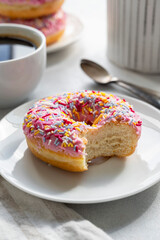 Pink donut with sprinkles and coffee cup for breakfast