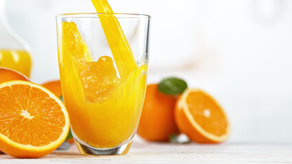 Orange juice pouring into glass. Fresh orange juice with oranges fruit in kitchen.