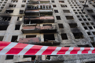 2022 Russian invasion of Ukraine bombed building destroyed warning tape foreground. Rocket bomb...