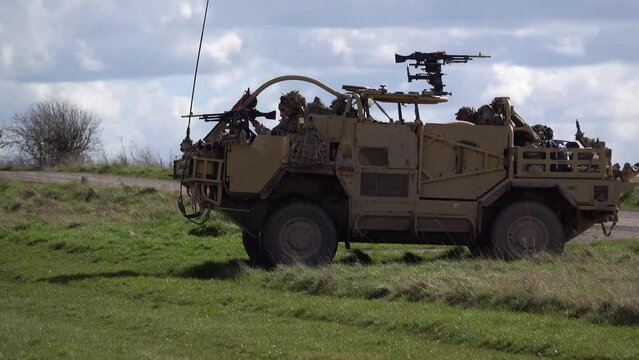 British army Supacat Jackal 4x4 rapid assault, fire support and reconnaissance vehicle in action across open countryside on a military battle training exercise