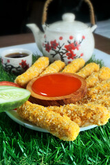 Nugget sticks fish fried crunchy line up around with cucumber tomato ketchup with teapot on artificial grass