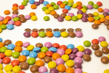 Chocolate candies of different colors laid out on a white background. The candies are cut in half. Harmful baby food