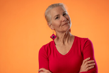 Portrait of beautiful smiling mature woman on orange color background, with copy space for product or sale.