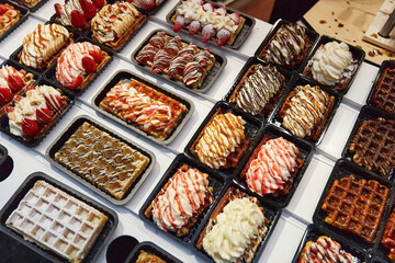 Various of traditional Belgian waffles topped with chocolate, speculoos, whipped cream and fruit...