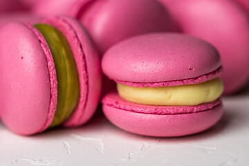 Macarons closeup on white wooden background. Sweet and colourful pink french macaroons. Cooking at home.
