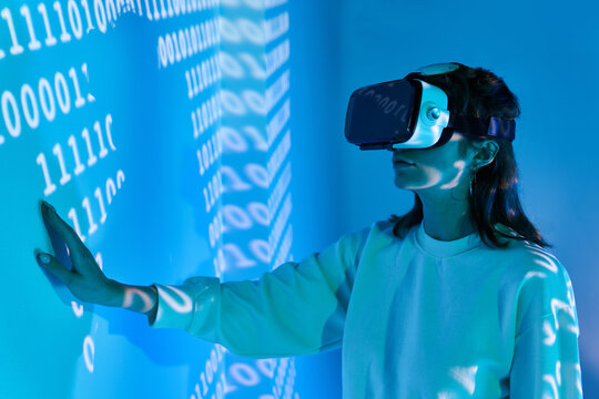 Woman in VR headset near wall with binary code