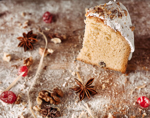 A piece of Easter dessert in a cut on a wooden table with flour and dried fruits on a black background