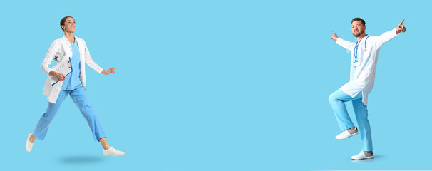 Happy female and male doctors on blue background with space for text