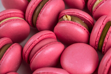 Macarons closeup on white wooden background. Sweet and colourful pink french macaroons. Cooking at home.