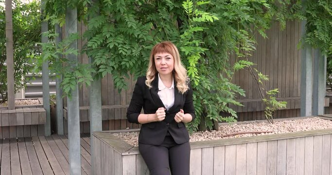 a beautiful girl with long blonde hair in a business suit gives an interview. blogger. journalist. news. A young business woman gives interviews about her company to journalists. an interview in a par