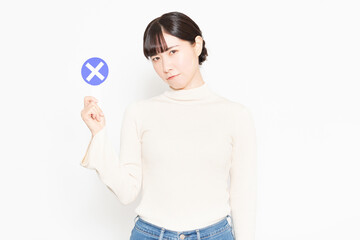 白い背景の前に立ってNGのプラカードを見せている女性