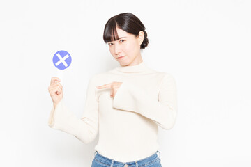 白い背景の前に立ってNGのプラカードを見せている女性