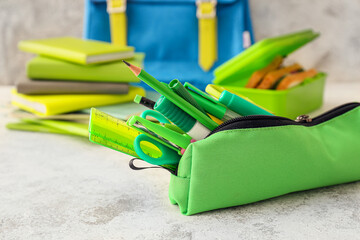 Green pencil case with stationery on light background, closeup