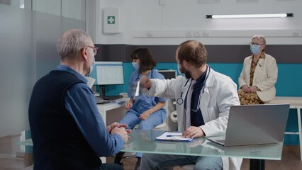 General practitioner analyzing radiography results in office, explaining x ray scan diagnosis to elder patient at checkup visit examination. Doctor and old man with face mask at consultation.