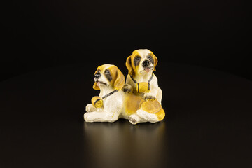 The statuette of two puppy dogs on a black background. Animal friends saint bernard with case a coin. Loyalty symbol concept. Close-up decor isolated. - Powered by Adobe