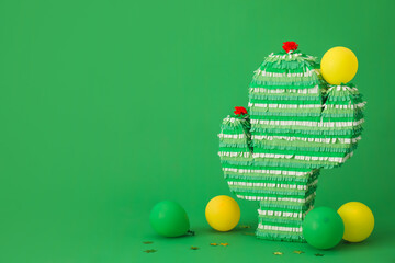 Mexican pinata in shape of cactus and balloons on green background © Pixel-Shot