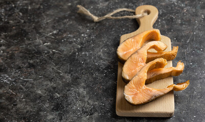 smoked, sliced trout on a dark wooden board with a place to copy. Selective focus.
